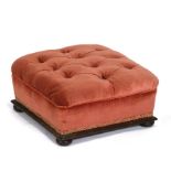 A Victorian upholstered footstool on four compressed bun feet.