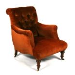 A Victorian button backed upholstered armchair on turned front supports.