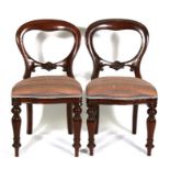 A pair of mahogany balloon back dining chairs with upholstered seats, on turned front supports.