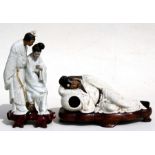 A Japanese crackle glaze figural group depicting a robed man and lady reading a book, on hardwood