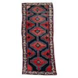 A Persian Hamadan handmade woollen runner with geometric design on a deep red ground, 290 by