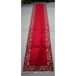 A Persian Tabriz woollen hand knotted runner with foliate borders on a claret ground, 465 by