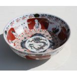 A Japanese footed bowl decorated with figures surrounding a central dragon, 24cms (9.5ins)