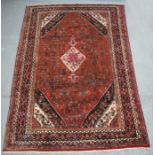 A Persian Hamadan woollen hand knotted rug with stylised central medallion on a red ground, 290 by