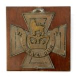 A WW1 trench art bronze copy of the Victoria Cross with mounting bolts attached to a hardwood shield