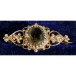 A Victorian yellow metal brooch set with a large oval pale green stone, 3.5cms (1.75ins) wide.