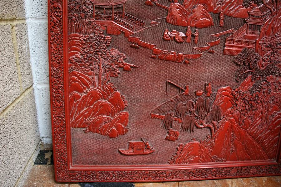 A large Chinese carved red cinnabar panel depicting a mountainous river scene within a foliate - Image 9 of 13