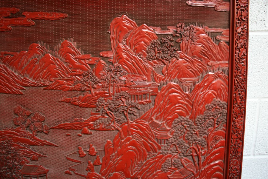 A large Chinese carved red cinnabar panel depicting a mountainous river scene within a foliate - Image 6 of 13