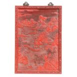 A large Chinese carved red cinnabar panel depicting a mountainous river scene within a foliate