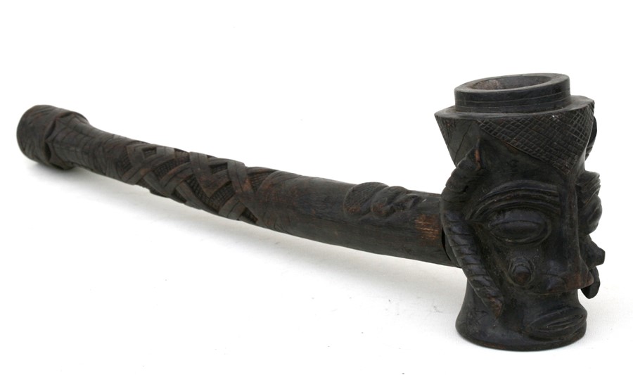 A large African carved wooden pipe, the bowl in the form of a stylised head, 60cms (23.5ins) long.