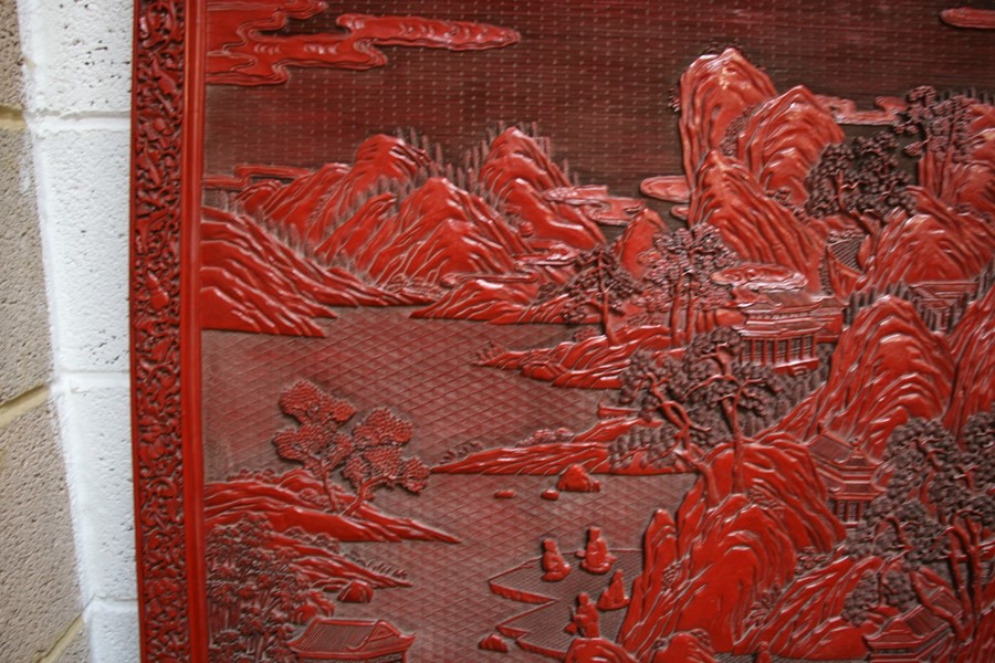 A large Chinese carved red cinnabar panel depicting a mountainous river scene within a foliate - Image 5 of 13