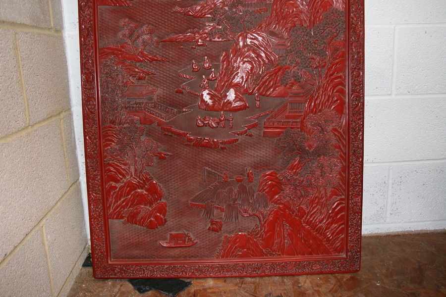 A large Chinese carved red cinnabar panel depicting a mountainous river scene within a foliate - Image 2 of 13