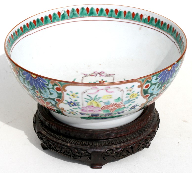 A 19th century Chinese famille rose bowl on a hardwood stand, 25cms (9.75ins) diameter.