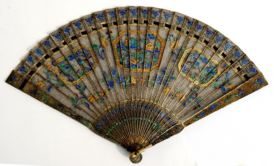 A Chinese silver gilt & enamel filigree brise fan decorated with buildings within panels and foliate