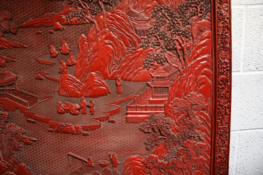 A large Chinese carved red cinnabar panel depicting a mountainous river scene within a foliate - Image 8 of 13