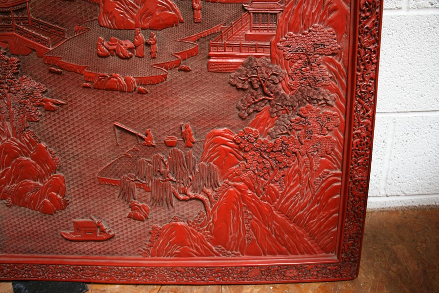 A large Chinese carved red cinnabar panel depicting a mountainous river scene within a foliate - Image 10 of 13