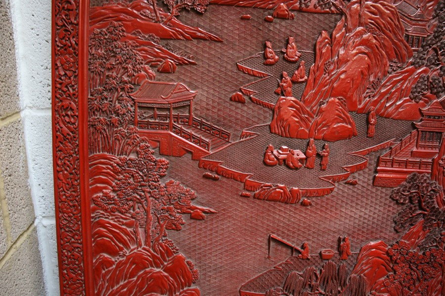 A large Chinese carved red cinnabar panel depicting a mountainous river scene within a foliate - Image 7 of 13