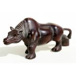 A Chinese hardwood carving in the form of a stylised rhinoceros, 28cms (11ins) long.