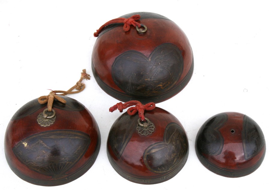 A set of four Japanese graduated lacquered bronze bells decorated with landscapes within panels, the