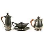 Two Tudric hammered pewter water jugs; together with an Art Nouveau pewter sauce boat (3).