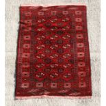 A Persian Turkoman woollen hand knotted rug with three rows of repeated guls, on a red ground, 120