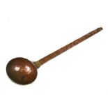 An Eastern hammered copper ladle, 52cms (20.5ins) long.