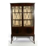 An Edwardian mahogany double door glazed display cabinet with shelved interior, on splayed legs,