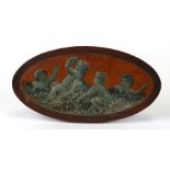A late 19th century painted oval mahogany panel depicting putti eating fruit, 24cms (9.5ins) wide.