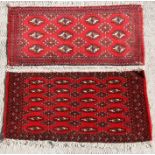 Two similar Persian Baluch woollen handmade rugs with geometric design on a red ground, each