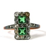 An Edwardian dress ring set with two green stones surrounded by white stones, approx UK size 'R'.