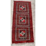 A Persian Baluch woollen hand knotted runner with geometric design on a red ground, 195 by 80cms (