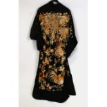 A Japanese kimono type robe decorated with cockerels and flowers on a black ground.Condition