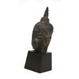 An antique South East Asian bronze Buddha head mounted on a later wooden plinth, the head 18cms (