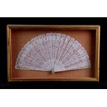 A Chinese Canton Export pierced bone brise fan, 30cms (12ins) wide, mounted in a glazed display case