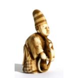 A 19th century Japanese carved ivory netsuke in the form of a robed boy riding a hobby horse, signed