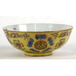 A Chinese porcelain bowl decorated with bats and peaches on a yellow ground, with six character