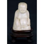 A Chinese bone figure in the form of a seated Buddha on a hardwood stand, 6cms (2.25ins) high.