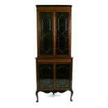 An Edwardian mahogany corner display cabinet, the pair of astragal glazed doors enclosing a