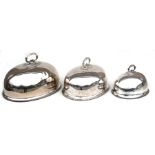 Three graduated silver plated meat domes, the largest 45cms (17.25ins) wide (3).