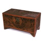 A deeply carved camphor wood trunk decorated with figures in sailing boats, 90cms (36ins) wide.