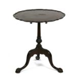 A mahogany tilt-top occasional table, the pie crust top on a turned column with tripod legs standing