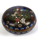 A Japanese cloisonne box and cover of compressed globular form, decorated with flowers on a black