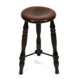 A 19th century elm stool on three turned legs joined by a cast iron stretcher.