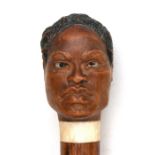 A 19th century malacca walking stick, the handle carved in the form of the head of a South Sea