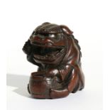 A Japanese carved hardwood netsuke in the form of a boy in a dragon costume beating a drum, two