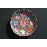 A large Chinese porcelain saucer dish decorated with peonies and other flowers on a red ground,