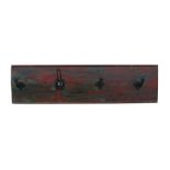 A set of coat hooks on a painted backboard, 107cms (42ins) wide.
