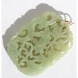 A Chinese pieced and carved jade pendant depicting a phoenix, dragon and lotus flowers, on a pair of