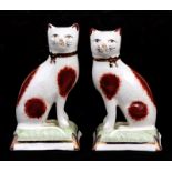 A pair of Staffordshire ware pottery figures in the form of seated cats, 11cms (4.25ins) high.