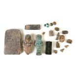 A collection of Egyptian artefacts including a figural scent bottle, a plaque with hieroglyphics,
